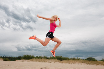 Fototapeta premium Jumping blond woman in summer sportswear.