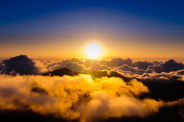 Sunrise over clouds and distant mountains from Haleakala Crater.