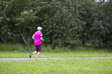 A runner jogging in the summer. Weather is a bit dull and it is raining.