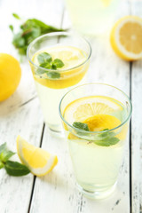 Fresh lemonade with lemon on white wooden background