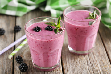 Blackberry smoothie in the glasses on grey wooden background