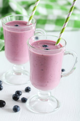 Fresh blueberry smoothie in the glasses on white wooden backgrou