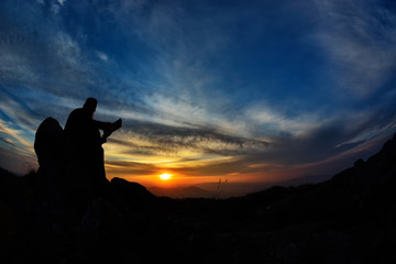 silhouette of priest reading in the sunset light, Romania, Ceahlau