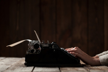 Hands writing on old typewriter over wooden background