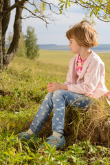 The girl with short blond hair sitting on the grass