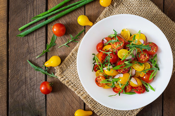 Salad of fresh cherry tomatoes with onion and arugula