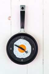 clock like a pan with fried egg on the wooden background