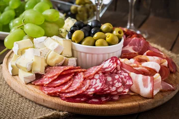 Rolgordijnen Antipasto catering platter with bacon, jerky, salami, cheese and grapes  © timolina