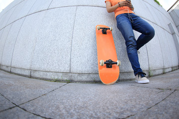 young skateboard use cellphone rest leaning on wall