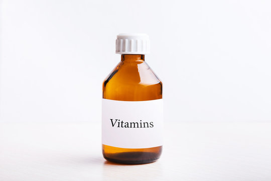 Vitamin bottle is on the table, on a white background.