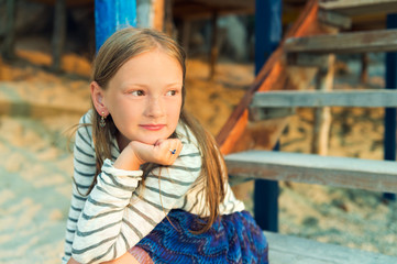 Little girl resting on the beach, watching the sunset, toned image