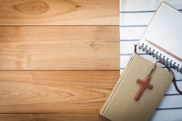 wooden Christian cross necklace on holy Bible on wood table