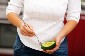 Young woman peeling avocado