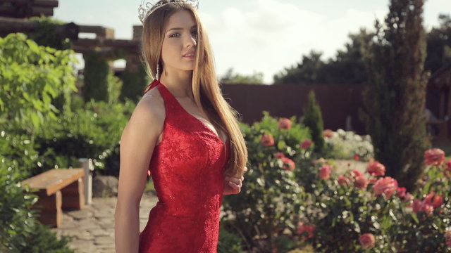 Lovely girl in a long red dress and with a crown on her head