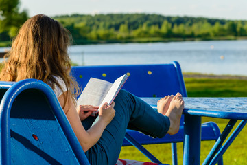 girl sitting on the shore of the lake and reading a book, landsc