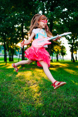 Little girl playing guitar in the park