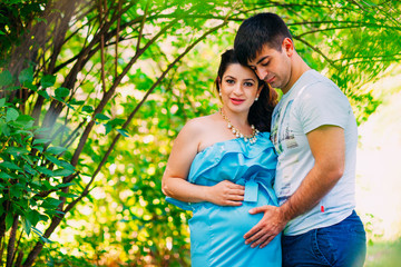Fototapeta premium Beautiful pregnant couple relaxing outside in the park.