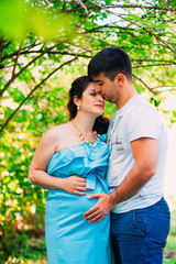Fototapeta premium Beautiful pregnant couple relaxing outside in the park.