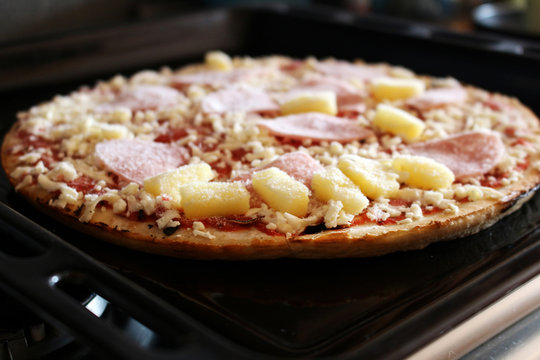 Frozen pizza with ham and pineapple on the plate
