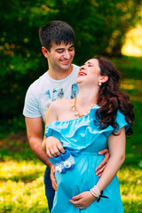 Fototapeta premium Beautiful pregnant couple relaxing outside in the park.