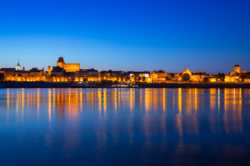 Obraz premium Panorama of Torun at night reflected in Vistula river, Poland