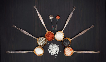 Assortment of salt. In vintage metal spoons on a wooden