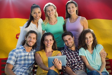 Composite image of smiling friends in the park using tablet pc