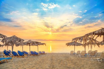 Vivid sunrise on a beautiful sandy beach with sunshade