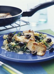 Fried trout fillets on pasta with olives and spinach sauce