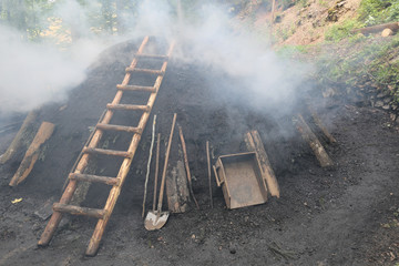 Rauchender Kohlenmeiler im Schwarzwald nach traditionellem Köhler - Handwerk aus  reinem...