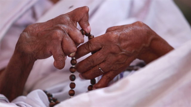Hands of an old woman disfigured by paralysis, sorted out the rosary.