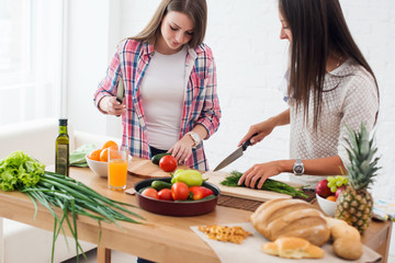 Two girls friends preparing dinner in a kitchen concept cooking