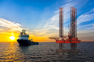 Tugboat and Oil Platform on offshore area at sunset.