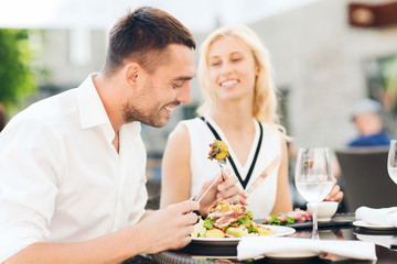happy couple eating dinner at restaurant terrace