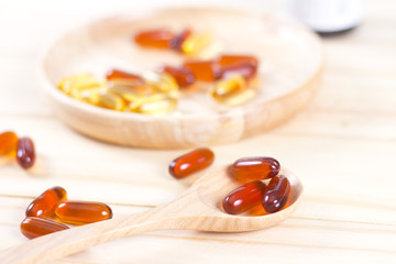 Closeup soft gelatin supplement fish oil capsule on wooden