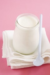 Obraz na płótnie Canvas Jar of yoghurt and plastic spoon on cloth
