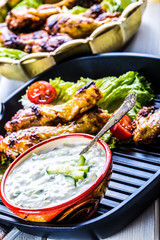 Tzatziki sauce. Tzatziki dressing. Tzatziki dressing with grilled chicken legs and fresh vegetable,lettuce leaf and cherry tomatoes. Grilled chicken legs, lettuce and tomatoes. Mediterranean cuisine.