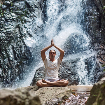 a young man engaged to a waterfall in the mountains of yoga