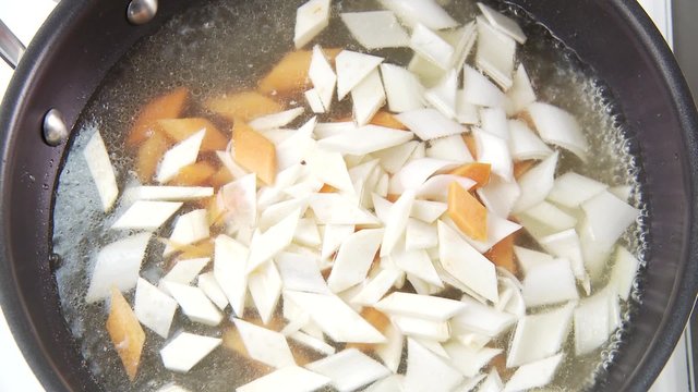 Vegetable pieces being cooked in salt water