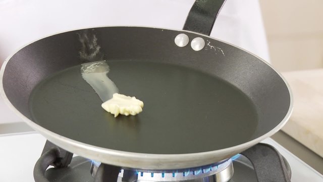Butter being melted in a pan and pancake dough being poured in