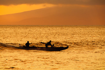 Two men paddling a Hawaiian outrigger canoe at sunset, Maui, Haw