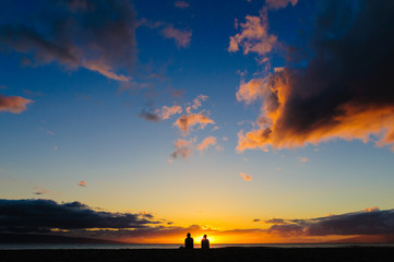 Naklejka na ściany i meble Couple watching the sunset on a beach in Maui Hawaii USA