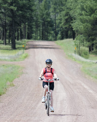 Naklejka premium A Woman Cyclist Rides a Forest Road