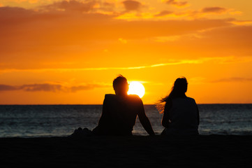 Couple watching the sunset on a beach in Maui Hawaii USA