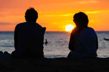 Couple watching the sunset on a beach in Maui Hawaii USA