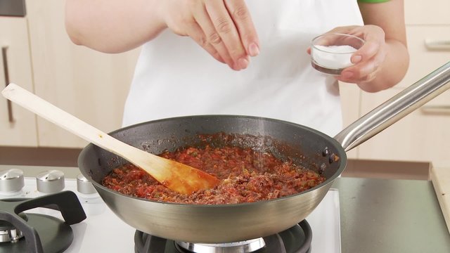 Minced meat sauce being seasoned with salt and pepper