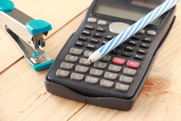 Calculator and Stapler with Pen on Wooden board