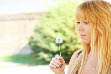 young woman in a garden holding a dandelion retro look filtered image 