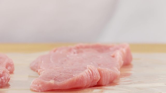 Veal escalopes being tenderised between layers of clingfilm