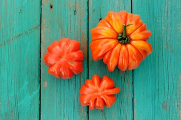 Three organic heirloom tomatoes on shabby wooden turquoise table
